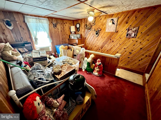 interior space with carpet flooring, wood walls, and ceiling fan