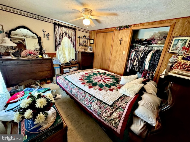 bedroom featuring ceiling fan, wood walls, a textured ceiling, a closet, and carpet floors