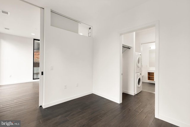 laundry area featuring stacked washer and dryer and dark hardwood / wood-style floors