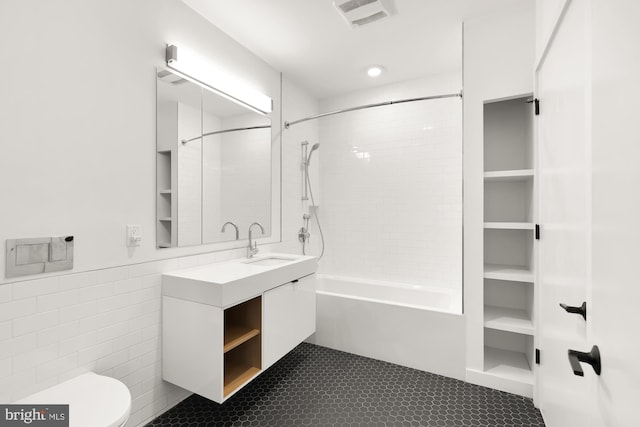 full bathroom featuring tile walls, tiled shower / bath, vanity, and toilet