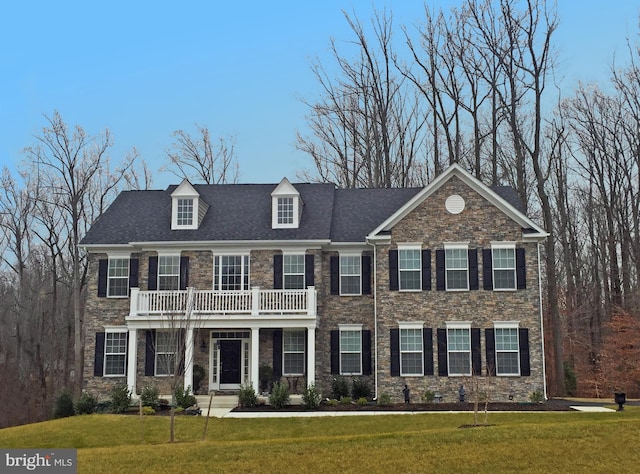 colonial home with a balcony and a front yard