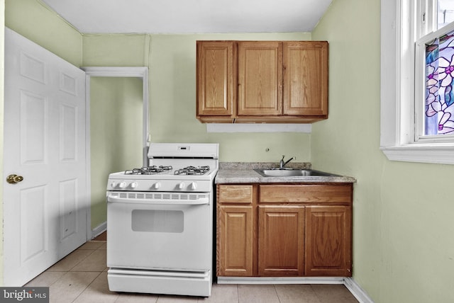 kitchen featuring light tile patterned floors, sink, and white range with gas cooktop