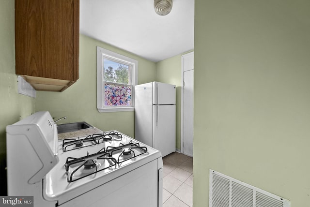 kitchen with white appliances, sink, and light tile patterned floors