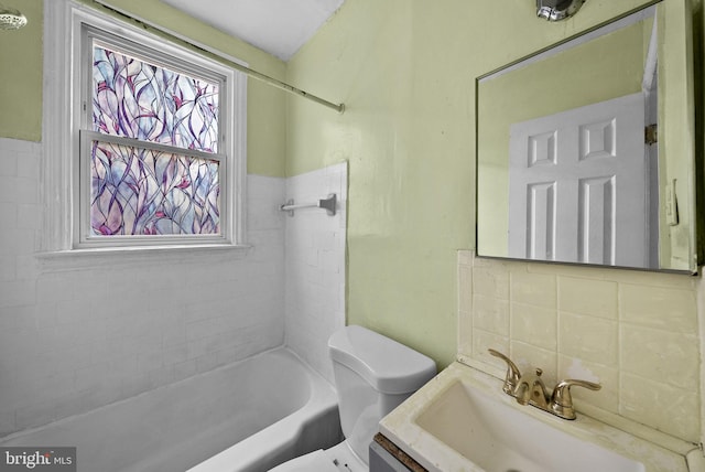 full bathroom with vanity, tile walls, tiled shower / bath combo, and toilet