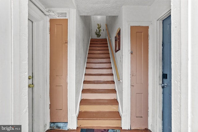 staircase with a textured ceiling