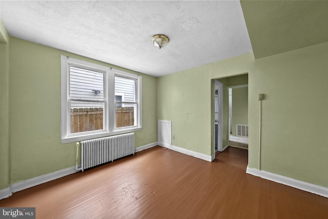 spare room with wood-type flooring, radiator, and a textured ceiling