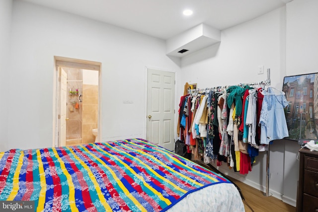 bedroom with hardwood / wood-style flooring and ensuite bath