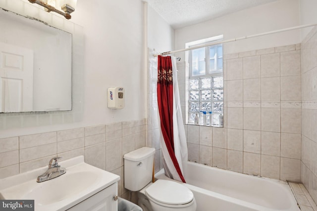 full bathroom with vanity, shower / bath combo, a textured ceiling, tile walls, and toilet