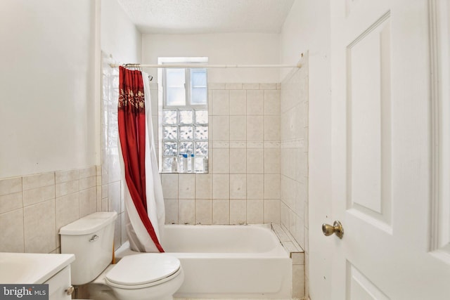 full bathroom featuring vanity, shower / bath combo with shower curtain, tile walls, toilet, and a textured ceiling