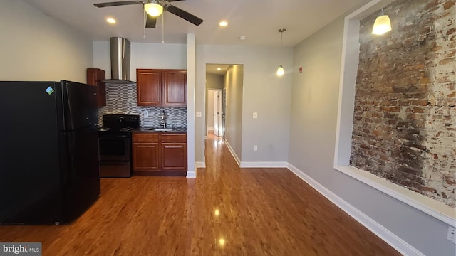 kitchen featuring ceiling fan, wall chimney exhaust hood, tasteful backsplash, black appliances, and hardwood / wood-style flooring