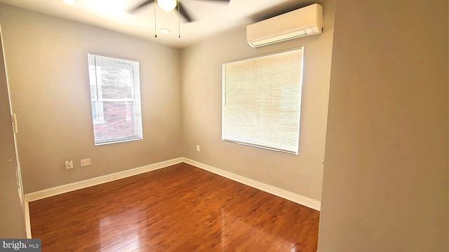 spare room with hardwood / wood-style flooring, ceiling fan, and a wall unit AC