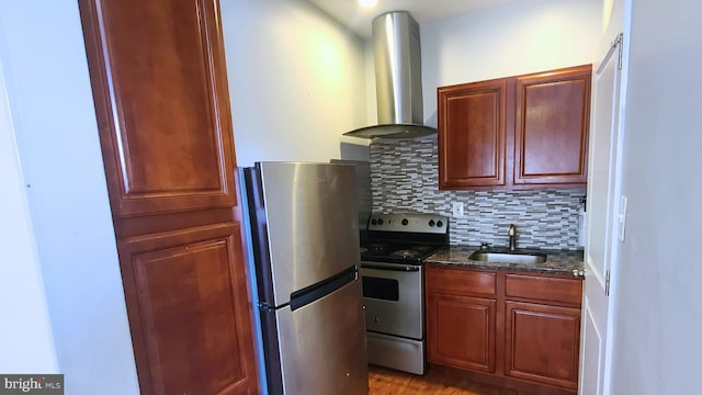 kitchen featuring sink, wall chimney exhaust hood, stainless steel appliances, backsplash, and dark stone counters