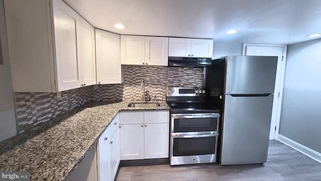 kitchen featuring light stone countertops, sink, backsplash, white cabinets, and appliances with stainless steel finishes