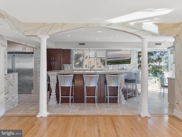 40110 Owens Ct, Fenwick Island, DE 19944 - kitchen with decorative columns, visible vents, a breakfast bar area, backsplash, and high end fridge