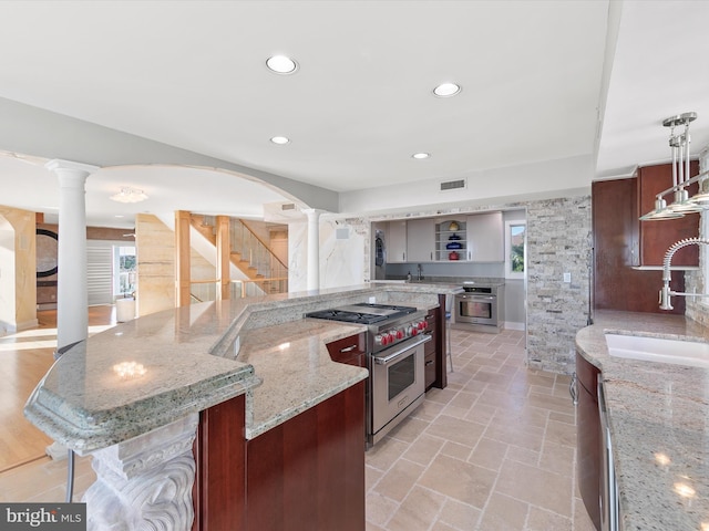 kitchen featuring stainless steel appliances, a wealth of natural light, sink, and light stone counters