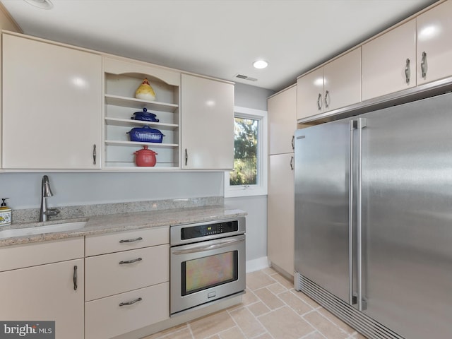 kitchen featuring light stone countertops, appliances with stainless steel finishes, sink, and white cabinetry