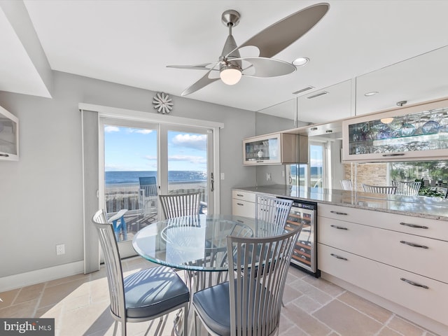 dining area featuring a water view, beverage cooler, and ceiling fan