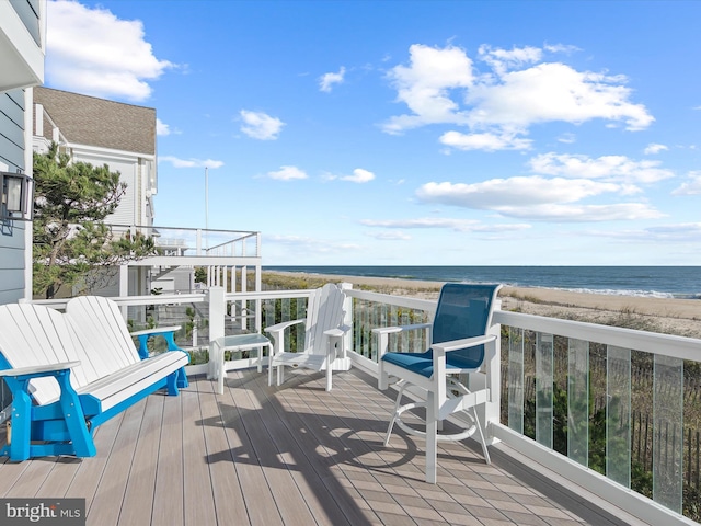 wooden terrace featuring a water view and a view of the beach