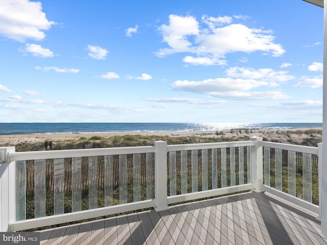 wooden deck featuring a water view and a view of the beach