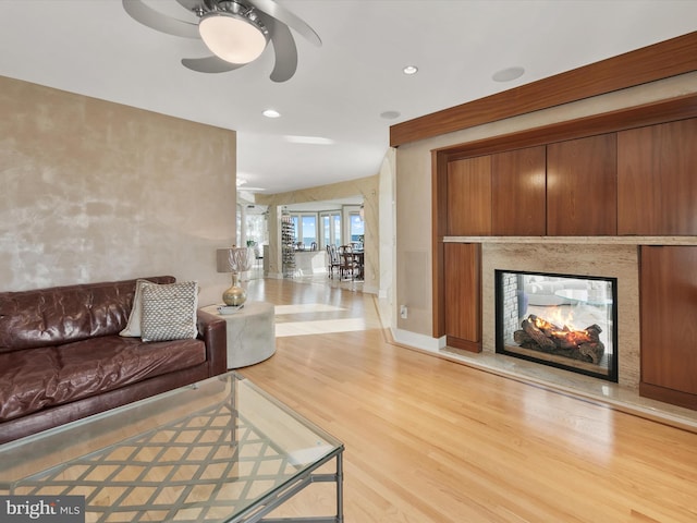 living room featuring a multi sided fireplace, ceiling fan, and light hardwood / wood-style floors