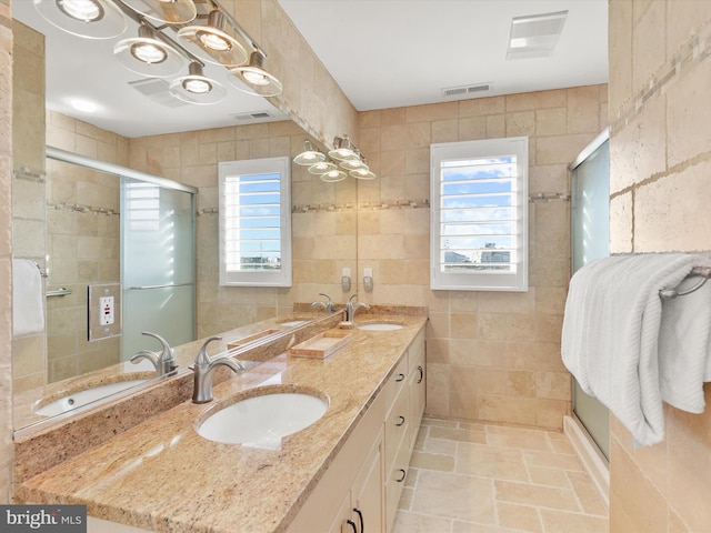 bathroom featuring an enclosed shower, a healthy amount of sunlight, vanity, and tile walls