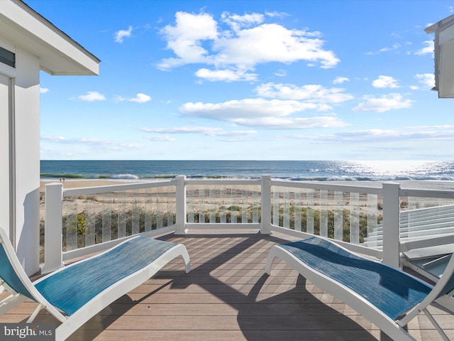 wooden terrace featuring a view of the beach and a water view