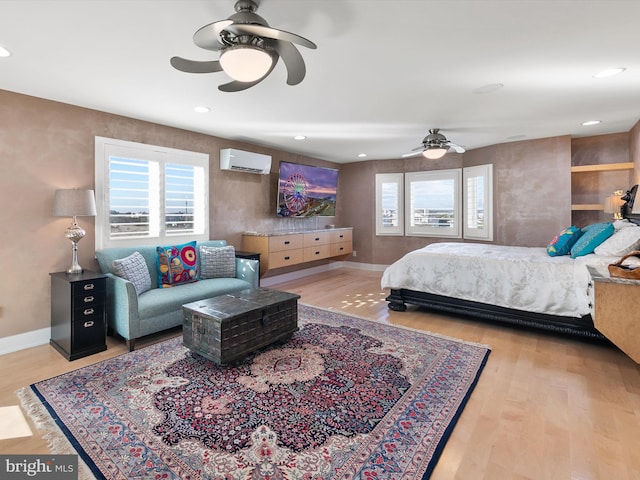 bedroom with ceiling fan, light hardwood / wood-style flooring, and a wall mounted AC