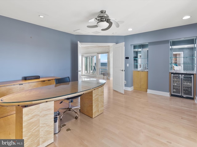 unfurnished office featuring ceiling fan, wine cooler, and light wood-type flooring