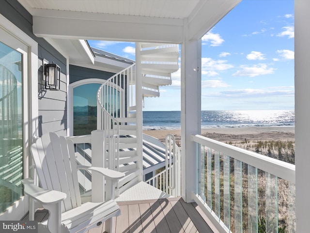 balcony with a water view and a view of the beach