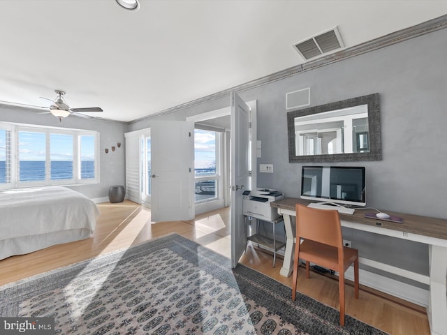 bedroom with ceiling fan, light wood-type flooring, multiple windows, and a water view