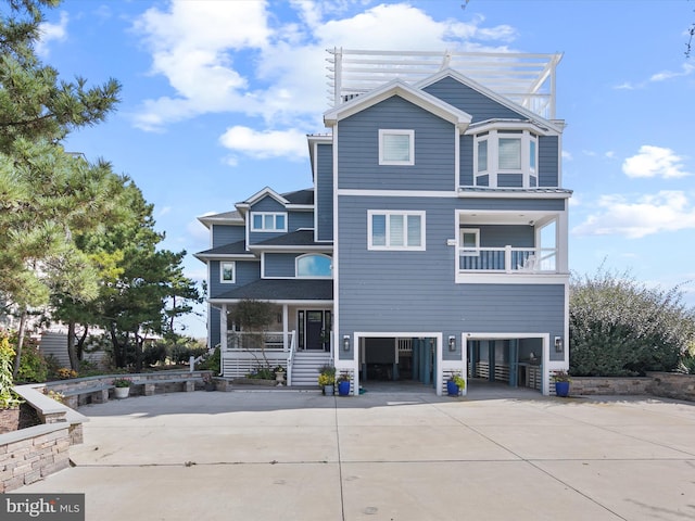 40110 Owens Ct, Fenwick Island, DE 19944 - view of front of house with concrete driveway, roof with shingles, an attached garage, and covered porch