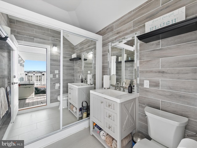 40110 Owens Ct, Fenwick Island, DE 19944 - bathroom with tile walls, toilet, vanity, vaulted ceiling, and a stall shower