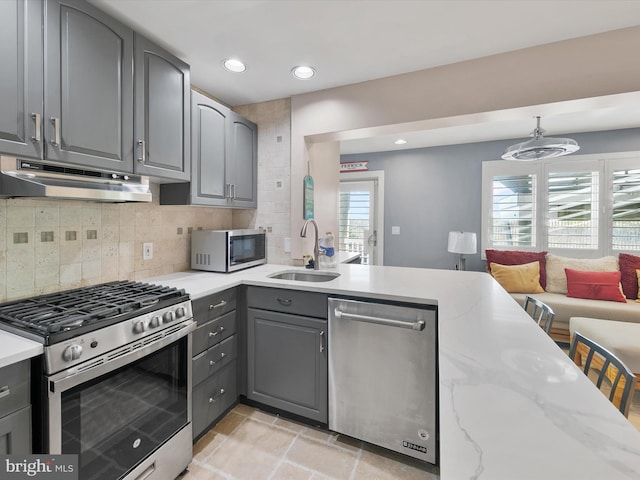 40110 Owens Ct, Fenwick Island, DE 19944 - kitchen with gray cabinets, backsplash, under cabinet range hood, stainless steel appliances, and a sink