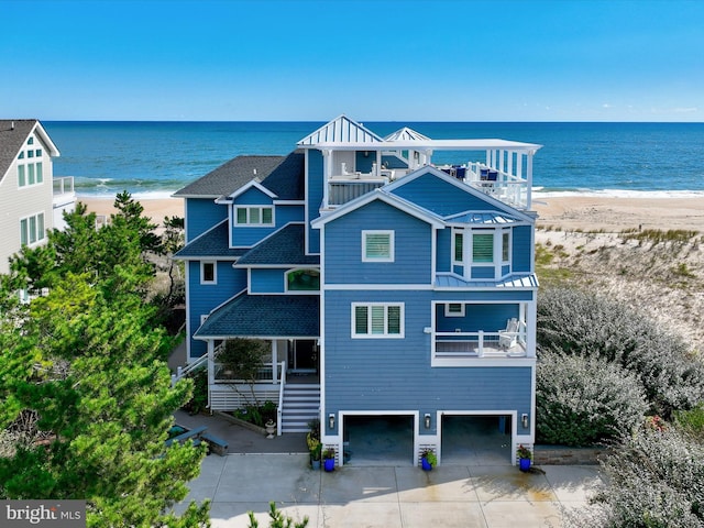 exterior space with a balcony, a garage, a water view, and a view of the beach