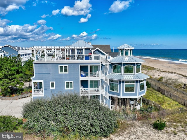 back of property featuring a view of the beach, a water view, and a balcony