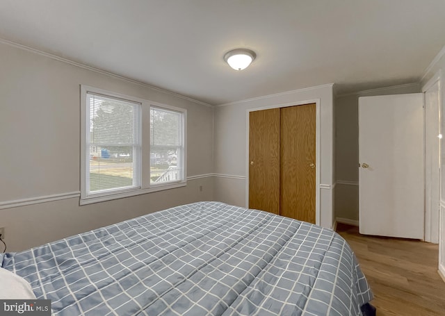 bedroom with a closet, light wood-type flooring, and crown molding