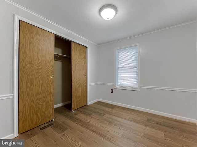 unfurnished bedroom featuring a closet, hardwood / wood-style flooring, and ornamental molding