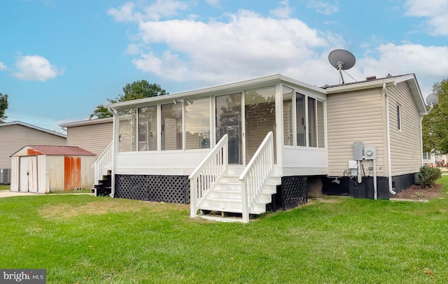 rear view of house featuring a shed, a yard, and a sunroom