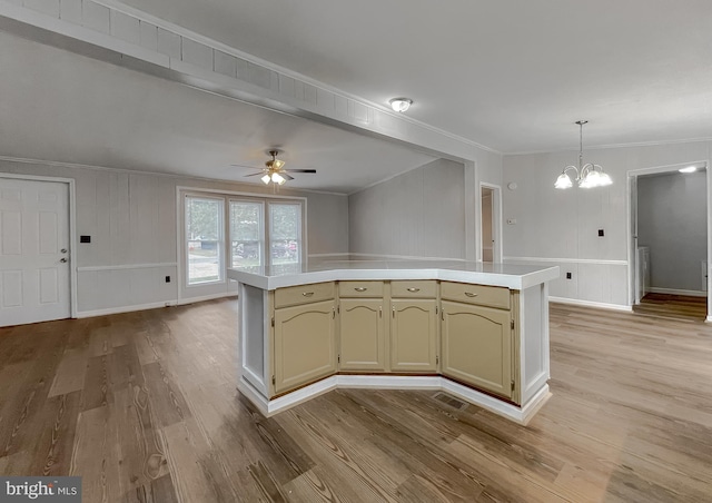 kitchen featuring light hardwood / wood-style floors, hanging light fixtures, ornamental molding, a center island, and ceiling fan with notable chandelier