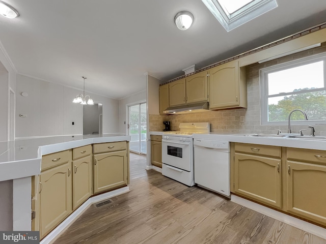 kitchen featuring white appliances, sink, pendant lighting, light hardwood / wood-style flooring, and an inviting chandelier