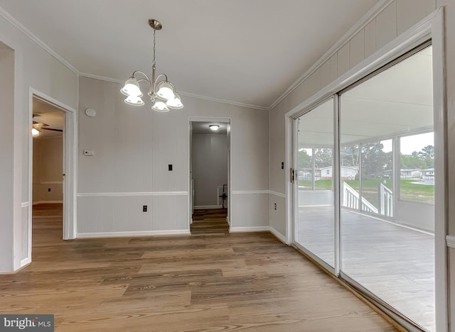 unfurnished dining area featuring lofted ceiling, crown molding, hardwood / wood-style flooring, and ceiling fan with notable chandelier