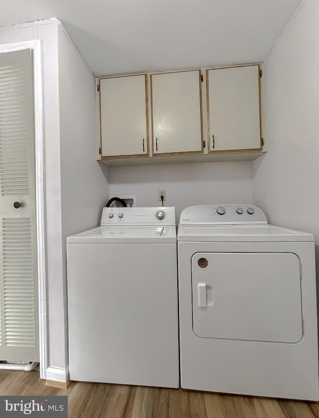 laundry area with cabinets, light hardwood / wood-style flooring, and independent washer and dryer