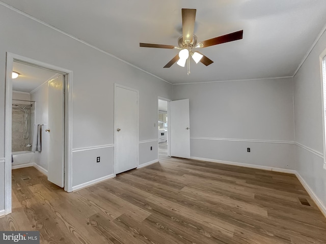 unfurnished bedroom featuring ensuite bathroom, ornamental molding, hardwood / wood-style flooring, and ceiling fan