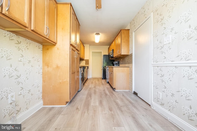 kitchen with washer / clothes dryer, appliances with stainless steel finishes, and light hardwood / wood-style flooring