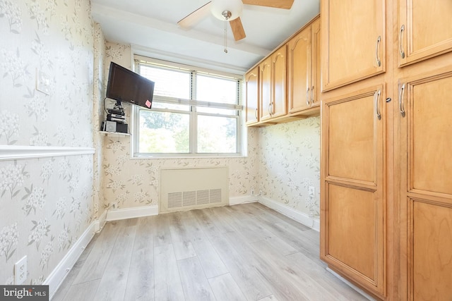 spare room featuring light wood-type flooring, radiator, and ceiling fan