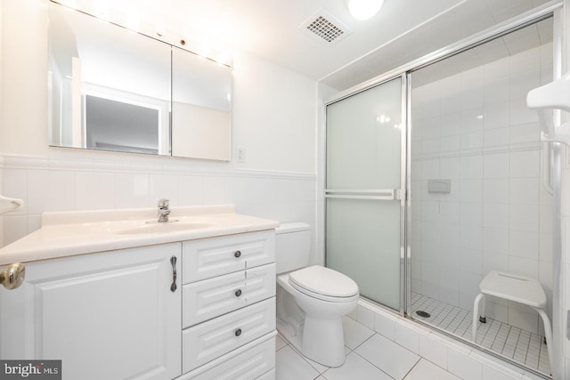 bathroom featuring tile walls, tile patterned flooring, a shower with shower door, vanity, and toilet