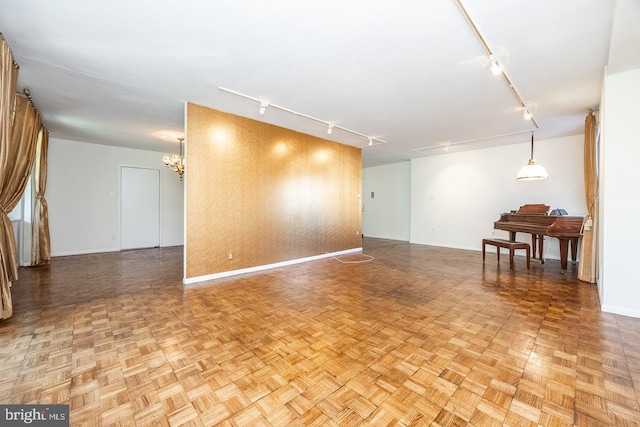 unfurnished room featuring light parquet floors, track lighting, and a notable chandelier