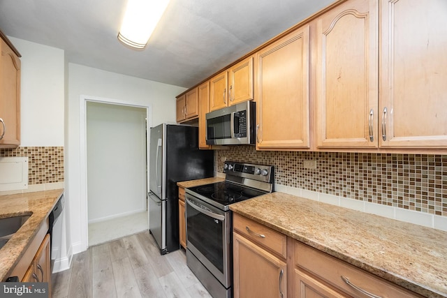 kitchen featuring decorative backsplash, light wood-type flooring, appliances with stainless steel finishes, and light stone countertops