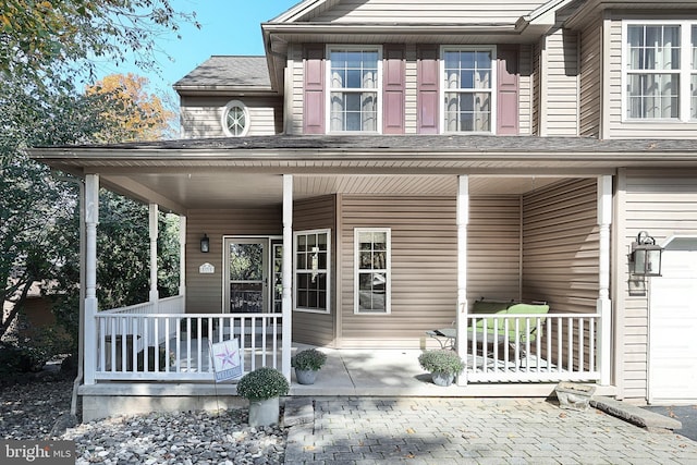 view of exterior entry featuring a garage and covered porch