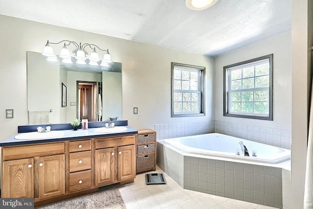 bathroom with tile patterned floors, a relaxing tiled tub, and vanity